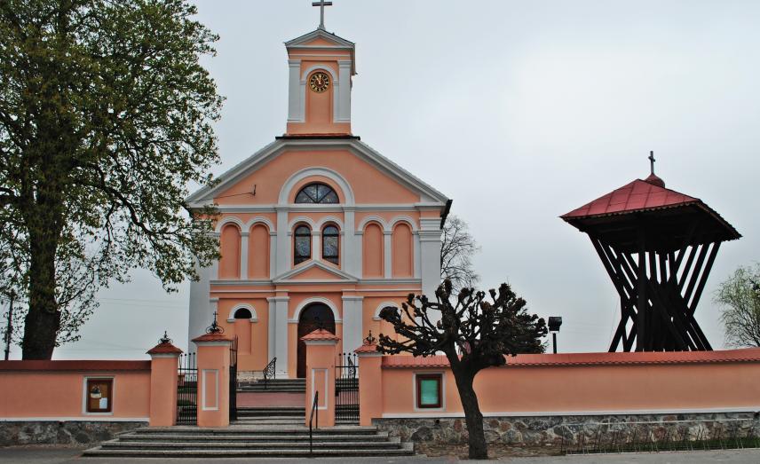 Różowy kościół w Świerczynie, przed nim dzwonnica 